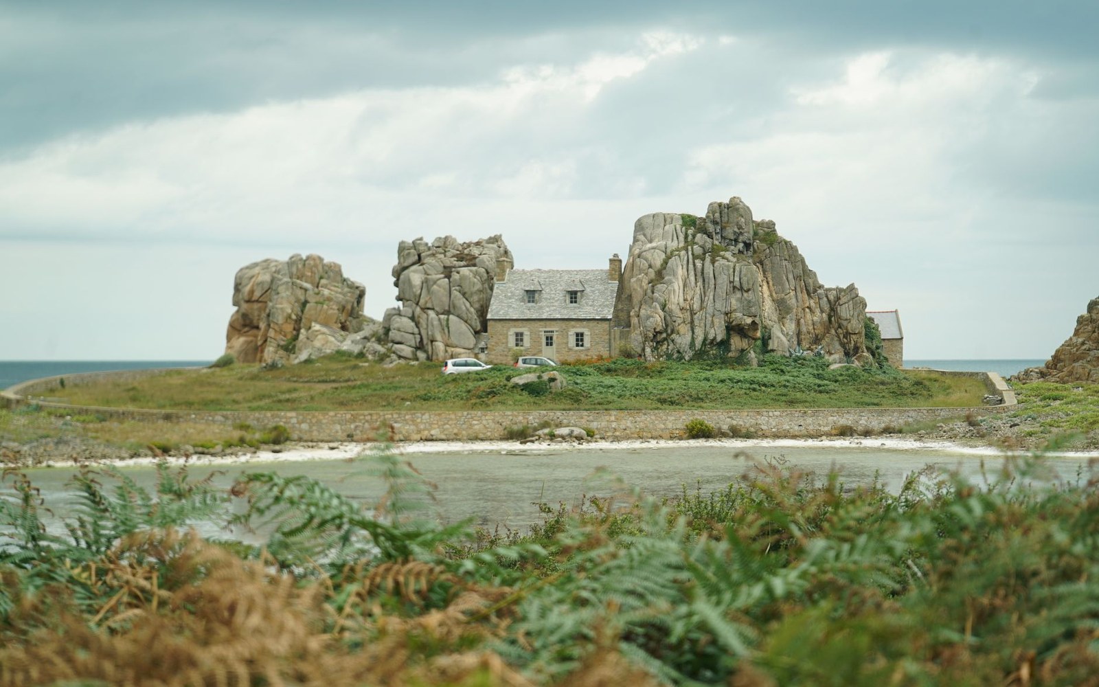Stone cottage wedged between massive granite boulders on a rocky coastal outcrop